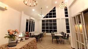 A spacious dining area with high ceilings and large windows, featuring a chandelier and a buffet table with various items. - Green Apple Villa (Sattahip)