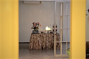 Ein Tisch ist für eine Mahlzeit gedeckt, es gibt einen Spiegel und eine Tischdecke mit Blumenmuster.