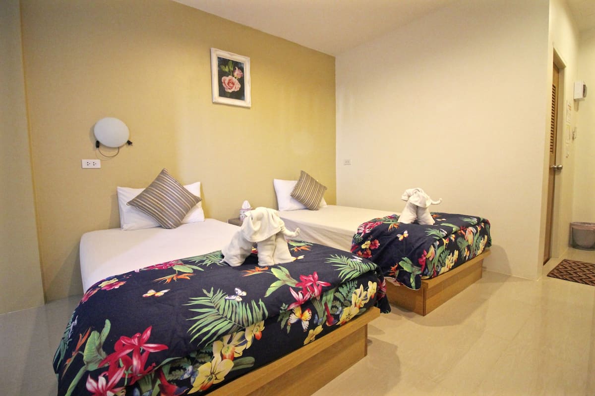 Quarto de hotel com duas camas, cada uma com roupa de cama florida e uma pequena estatueta de elefante.