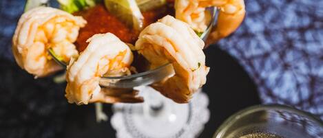 A glass bowl with shrimp and lime wedges.