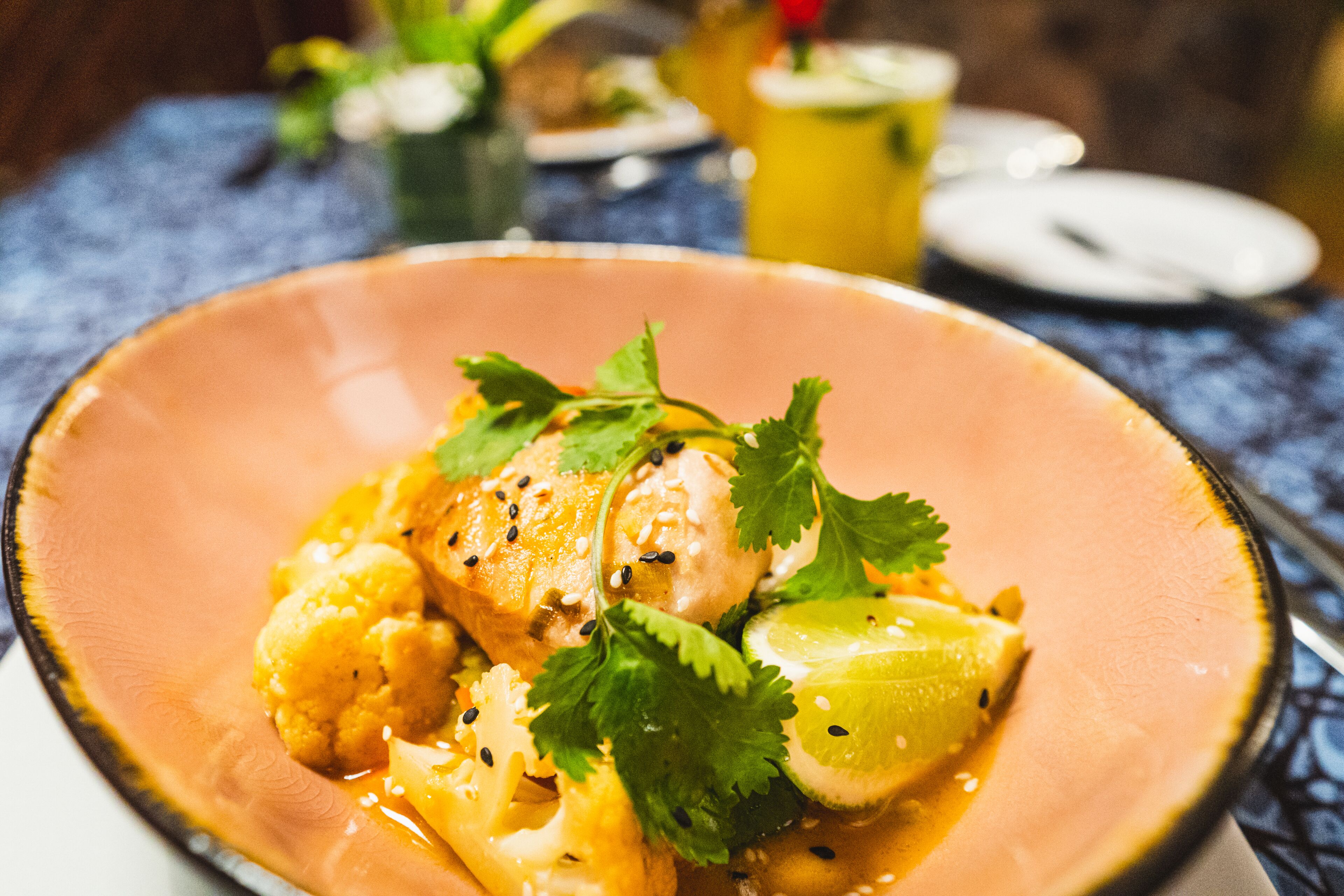 A plate of food with a creamy sauce, garnished with cilantro and sesame seeds.