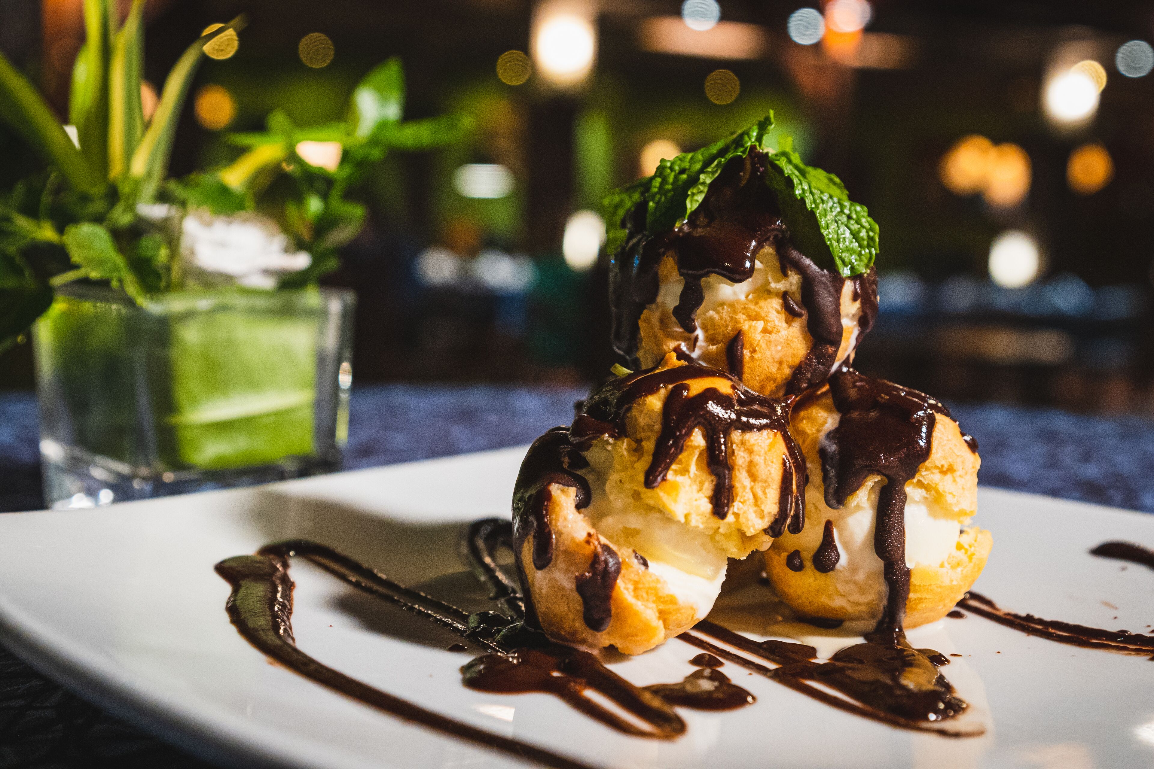 Un postre en un plato con salsa de chocolate y hojas de menta.