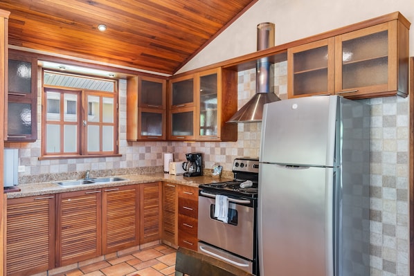 A kitchen with wooden cabinets, a stainless steel refrigerator, and a stove. - Hotel Villa del Sueño (Sardinal)