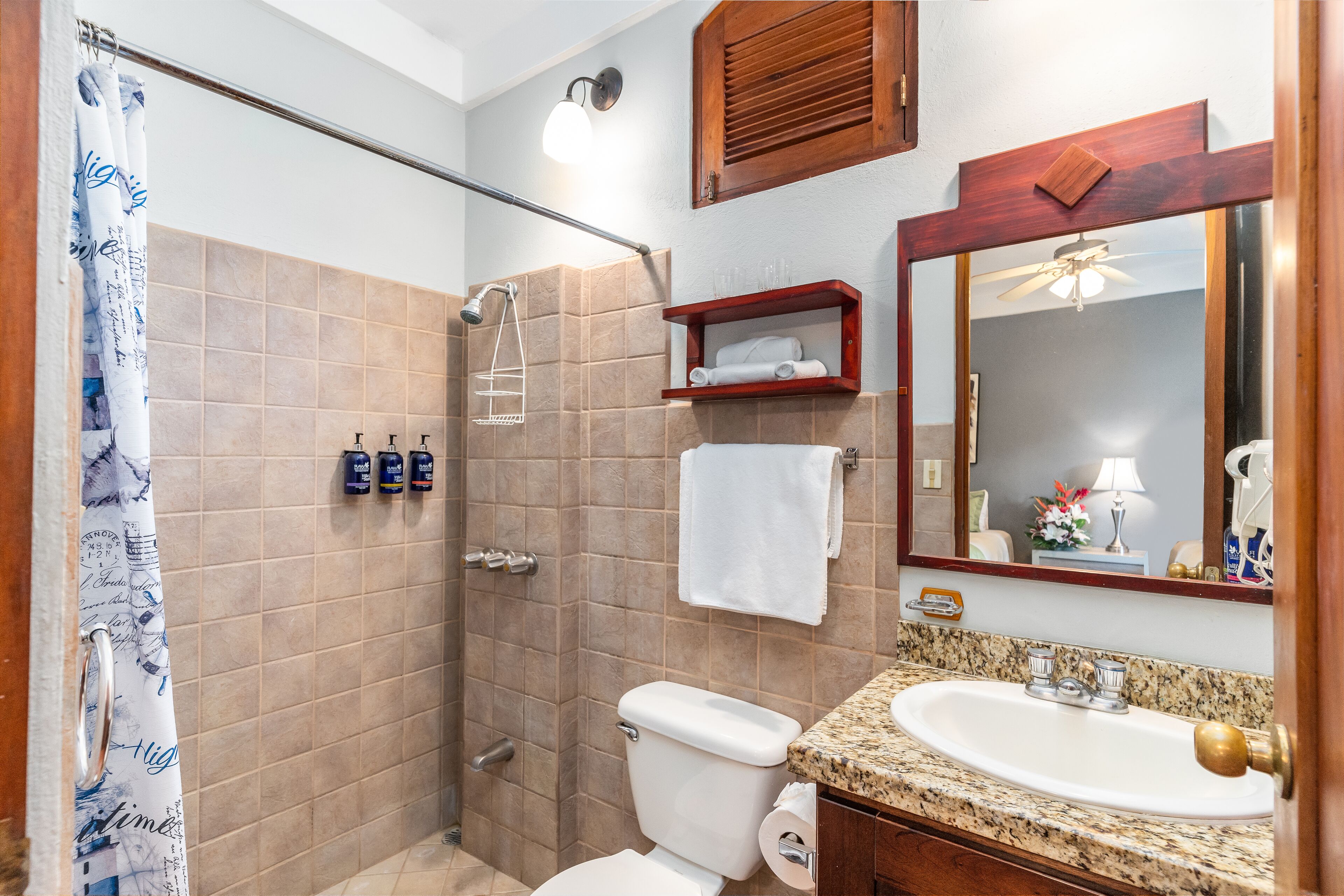 A bathroom with a shower, toilet, sink, and a mirror.