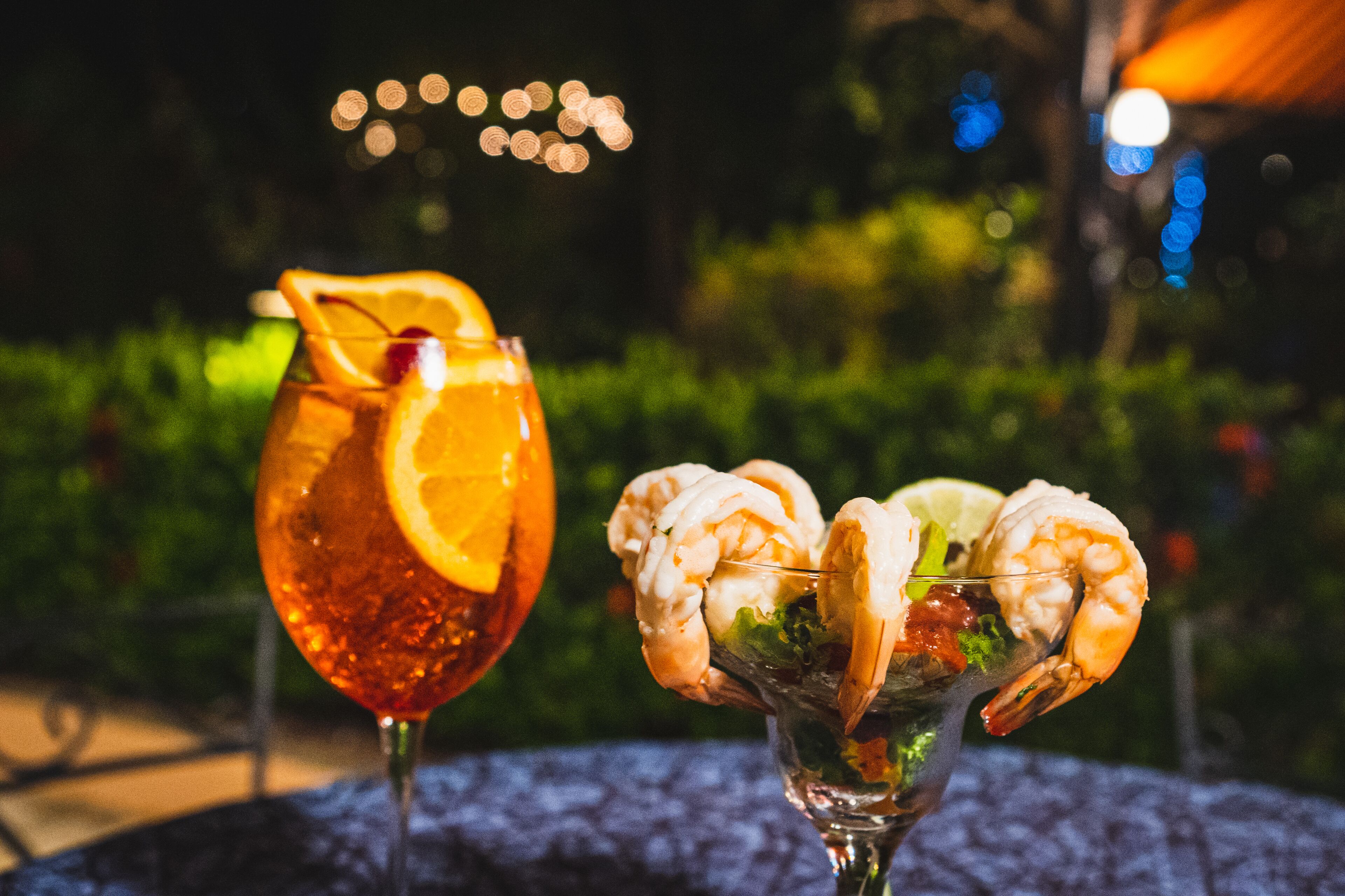Two drinks on a table with a blurred outdoor background.