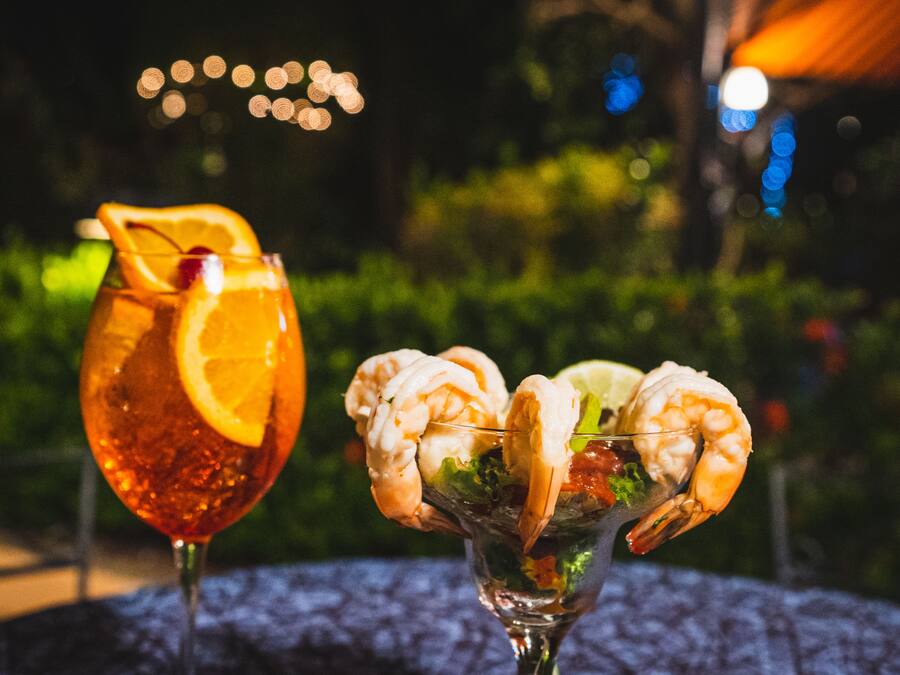 Two drinks on a table with a blurred outdoor background.