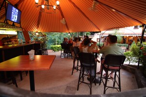 Un área de comedor al aire libre con mesas y sillas bajo una carpa grande.