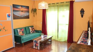 A living room with a green sofa, a wooden coffee table, and a painting of a sunset over the ocean.