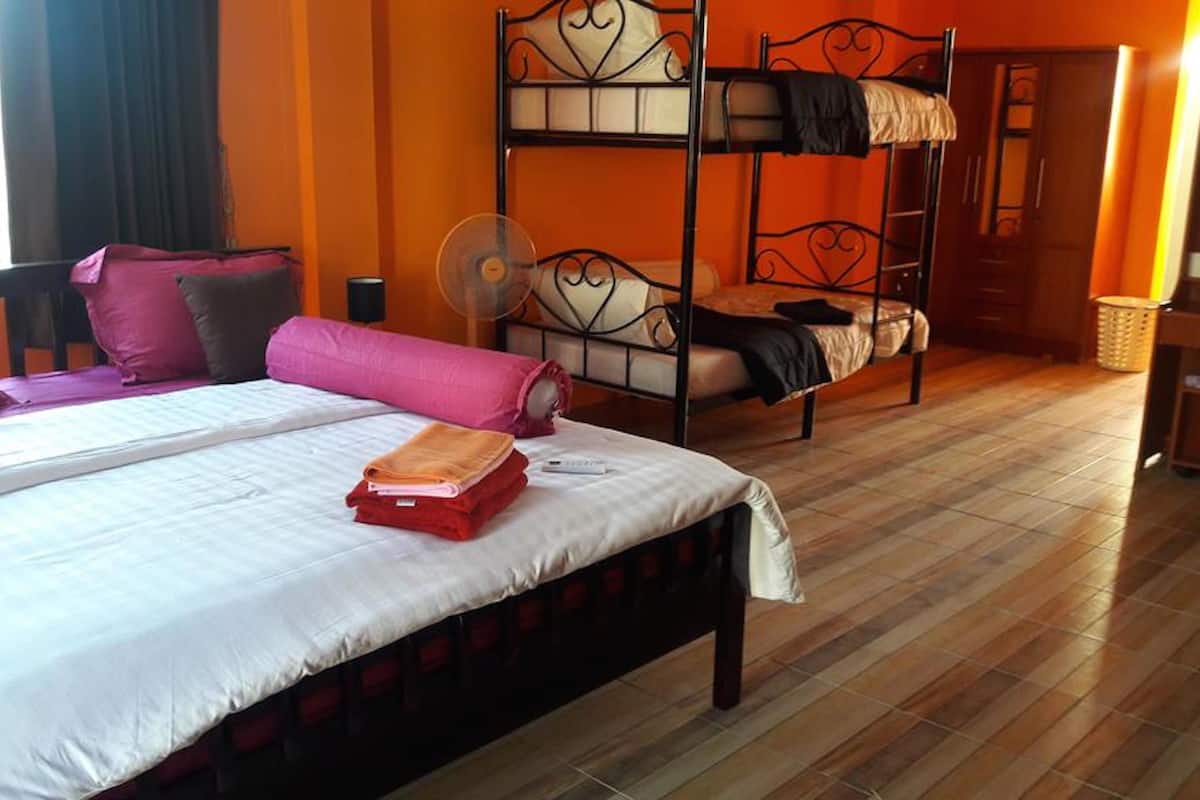 A room with a bunk bed, a single bed, and a wooden floor.