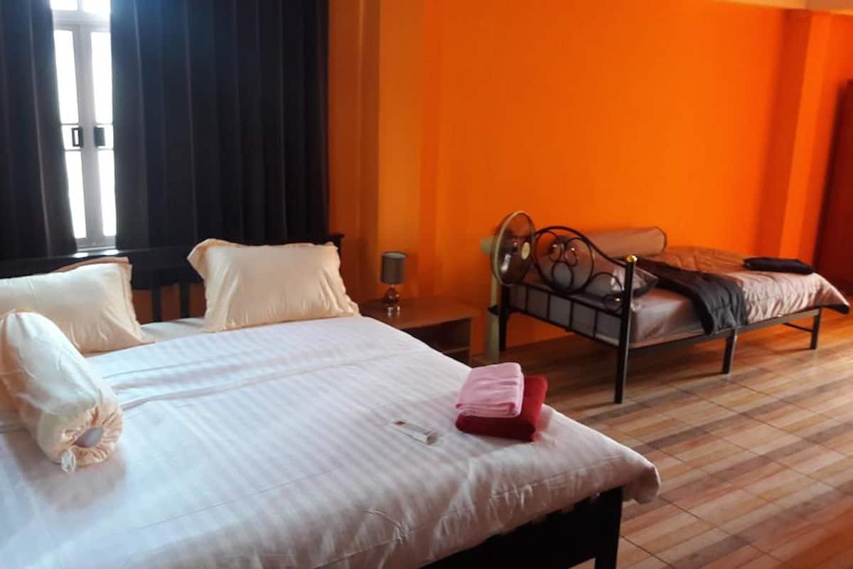 A hotel room with a large bed, a smaller bed, a bedside table, a lamp, and a wardrobe.