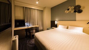 Ein Hotelzimmer mit Bett, Schreibtisch, Stuhl und einer Wand mit kreisförmigen Verzierungen.