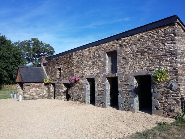 A stone building with multiple windows and a gravel driveway.
