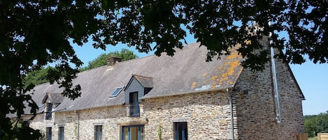A stone building with multiple windows and a sloped roof.