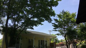 A yellow building with a porch, surrounded by trees and greenery. - Guests & Dogs House Hale Ilio (Ito)