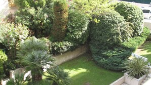 Een weelderige tuin met diverse planten en een klein zitgedeelte.