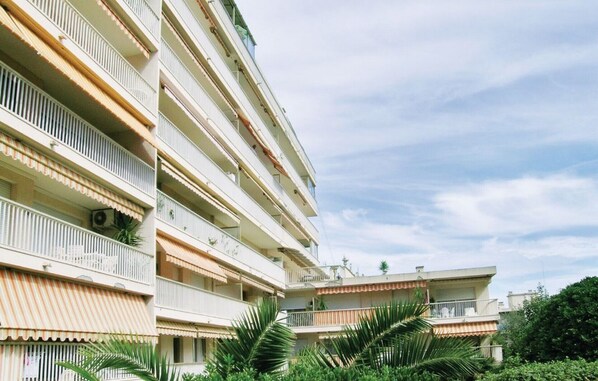 A multi-story residential building with balconies, a flat roof, and a clear sky.