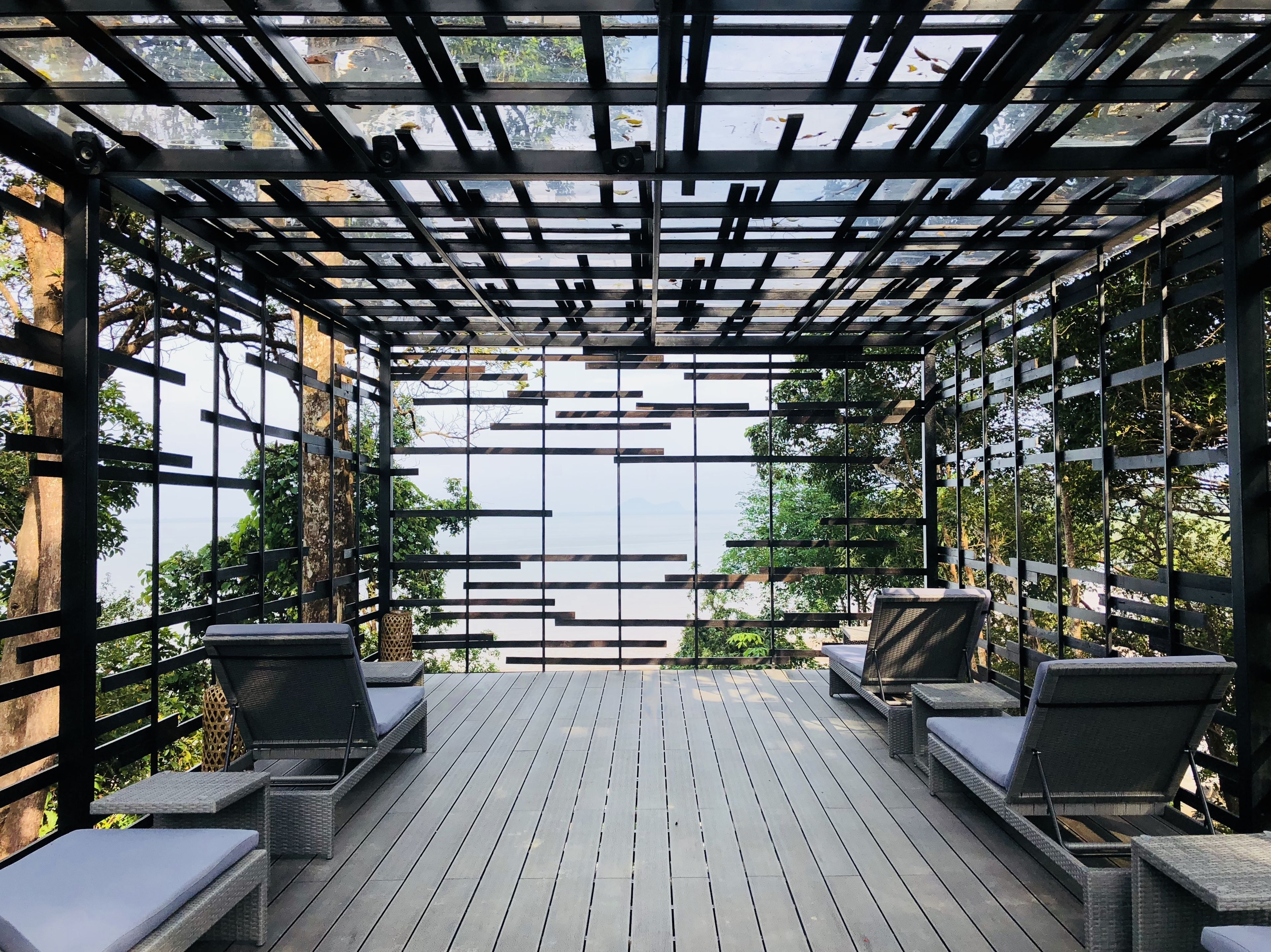 Una terraza techada al aire libre con piso de madera y barandillas de metal negro.