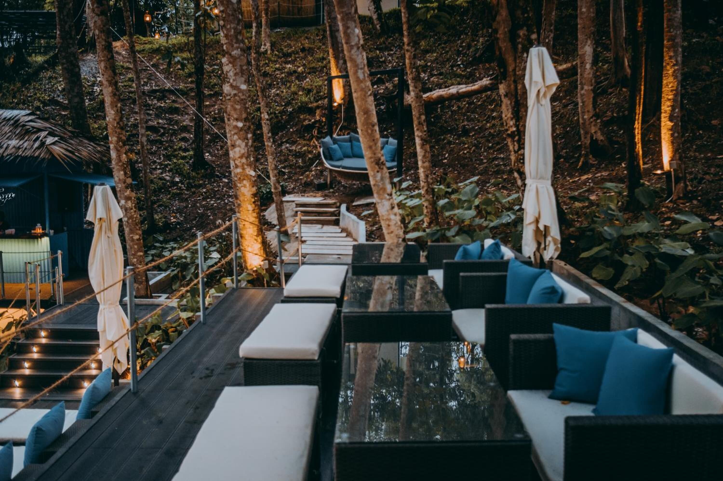 Un bar situé sur le toit, avec des places assises en plein air, un fauteuil suspendu et un escalier menant à un niveau supérieur.