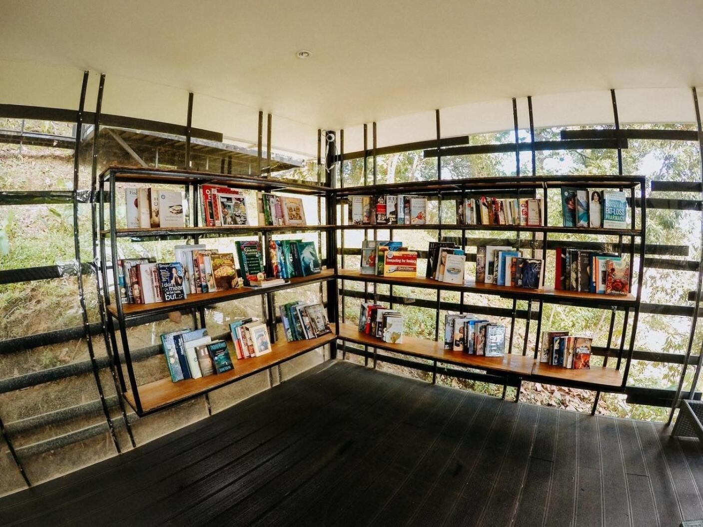 Una estantería de esquina con libros, un banco y vistas a zonas verdes.
