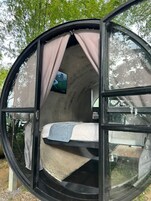 Habitación circular con cama, televisor y ventana con cortinas.