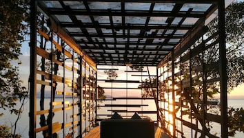 Un espacio de estar al aire libre cubierto con vistas al agua y al atardecer.