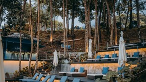 A rooftop lounge with multiple seating areas, including lounge chairs and sofas, surrounded by trees and plants. - The Culvert (Kuching)