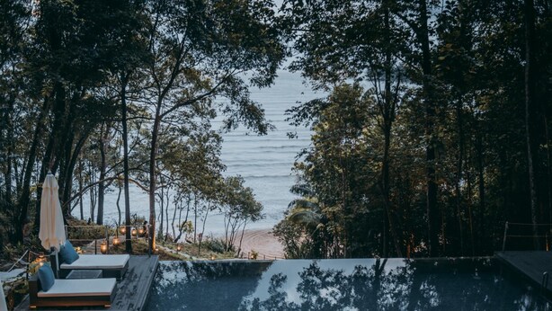 A pool area with lounge chairs and a view of the beach. - The Culvert (Kuching)