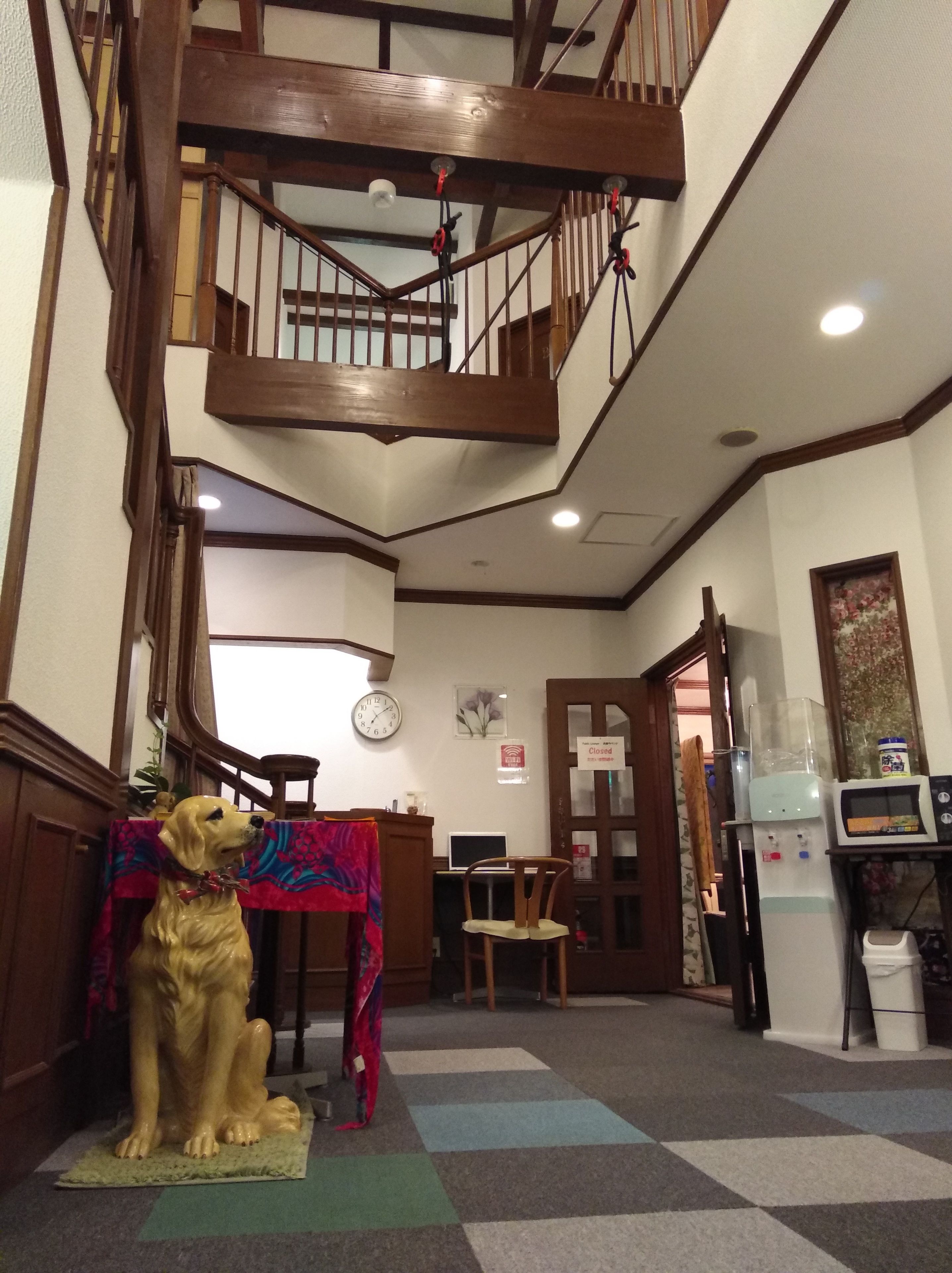 Un escalier avec des rampes en bois et une statue de chien au bas.