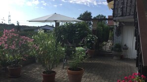 A courtyard with potted plants and a pergola with a white umbrella.
