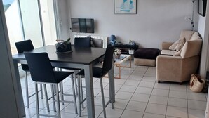 Una sala moderna con comedor, sofá y televisor montado en la pared.