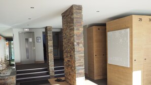 A modern interior with stone pillars, wooden lockers, and a staircase leading to another area. - 3 comfortable and bright rooms, beautiful view of Solaise and the Daille (Val-D'isère)