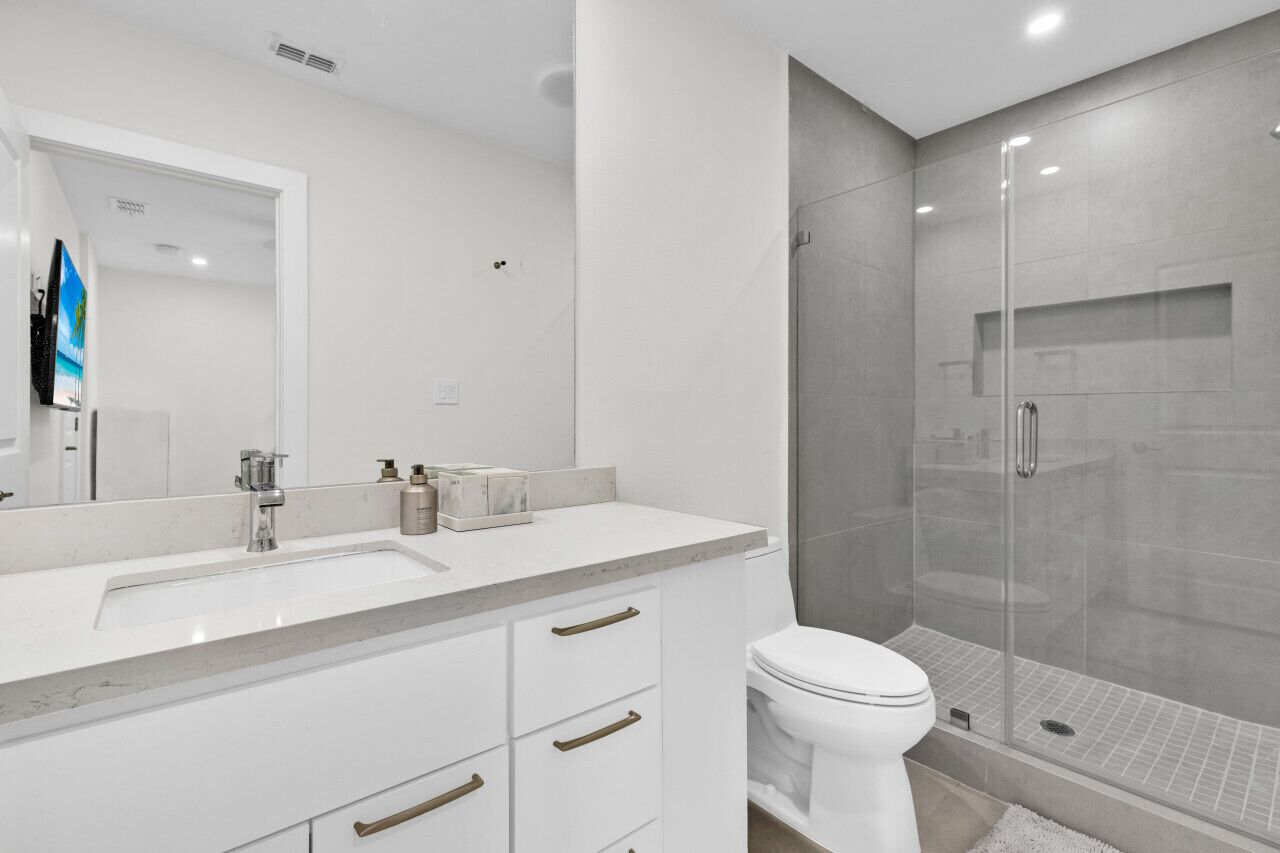 Une salle de bain moderne avec un grand miroir, un lavabo et des toilettes.