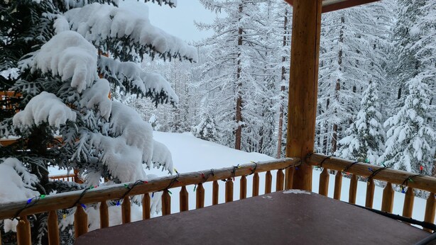 Ein Holzbalkon mit Blick auf verschneite Bäume.
