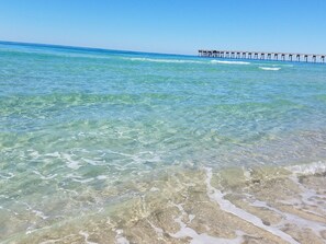 Um cais se estendendo sobre um mar azul e límpido, com o relevo subaquático visível.