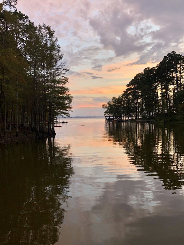 Un lago tranquillo con alberi su entrambe le rive e un molo che si protende nell'acqua.
