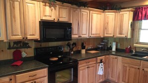 A kitchen with wooden cabinets, a black stove, and a microwave. - Beautiful Creekside Cabin 3 Bedroom Robbinsville, NC Perfect Family Location! (Robbinsville)