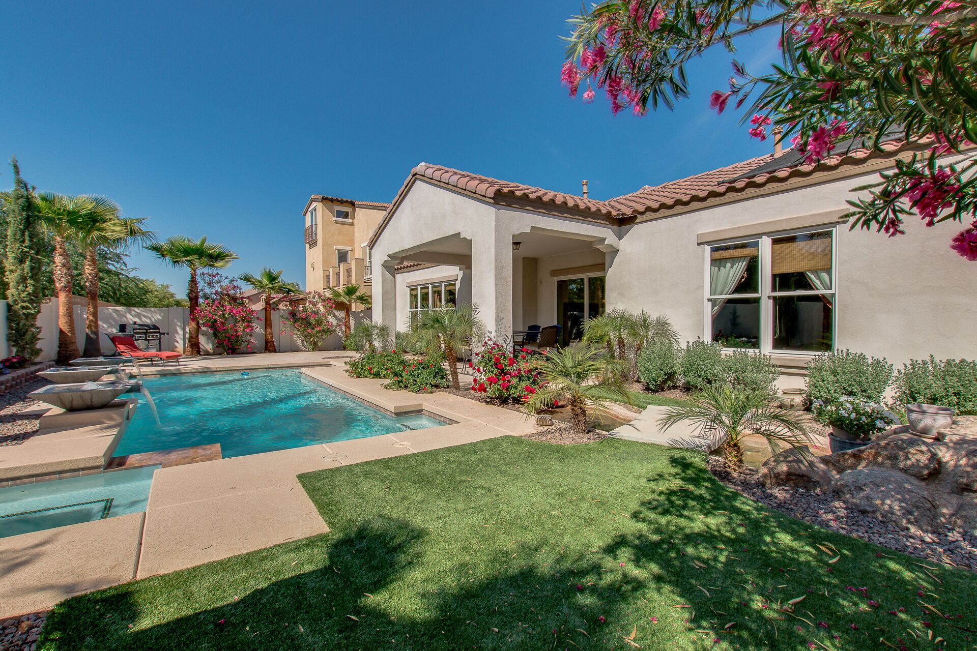 Ein Wohnhaus mit Swimmingpool, einer Terrasse mit Gartenmöbeln und einem gepflegten Garten mit verschiedenen Pflanzen und Blumen.
