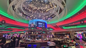 Un casino doté de nombreuses tables de jeux et d’un bar central.