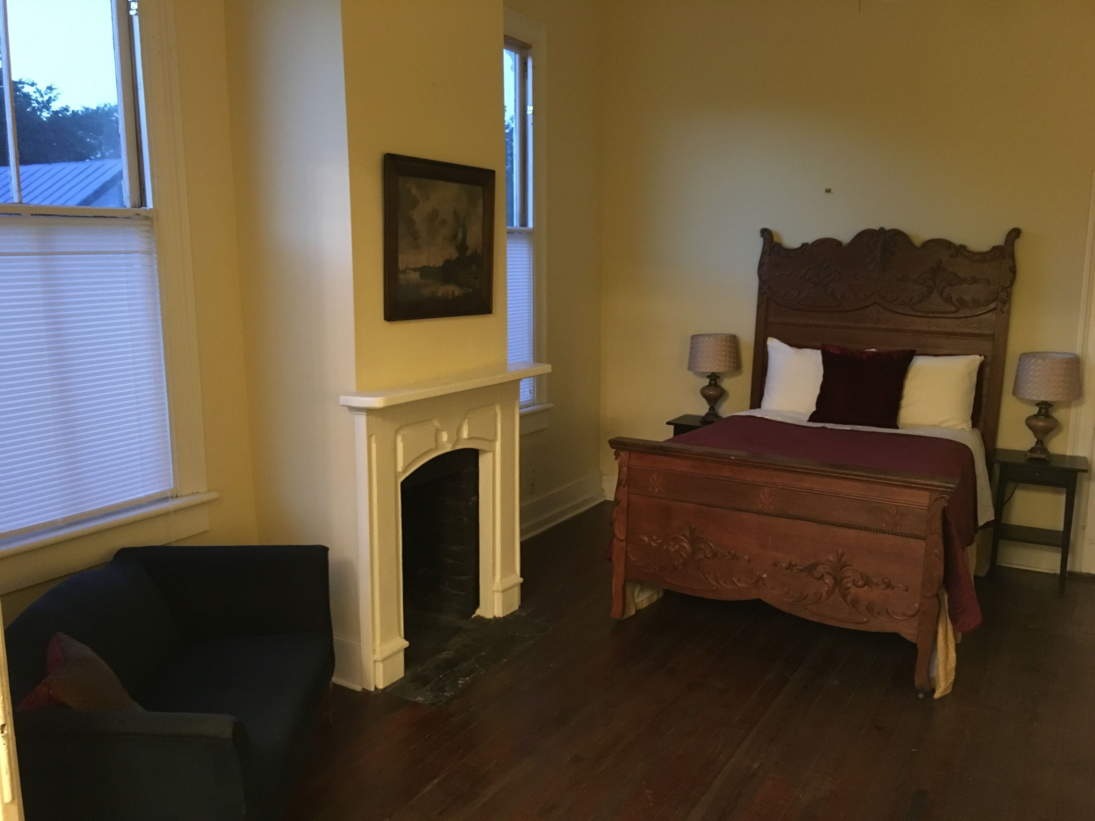 A bedroom with a wooden bed, a fireplace, and a nightstand with lamps.