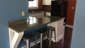 A kitchen with a granite countertop, white cabinets, a black refrigerator, and stainless steel bar stools. - Amazing view of Seneca Lake, close to wine trail and water activities (Geneva)