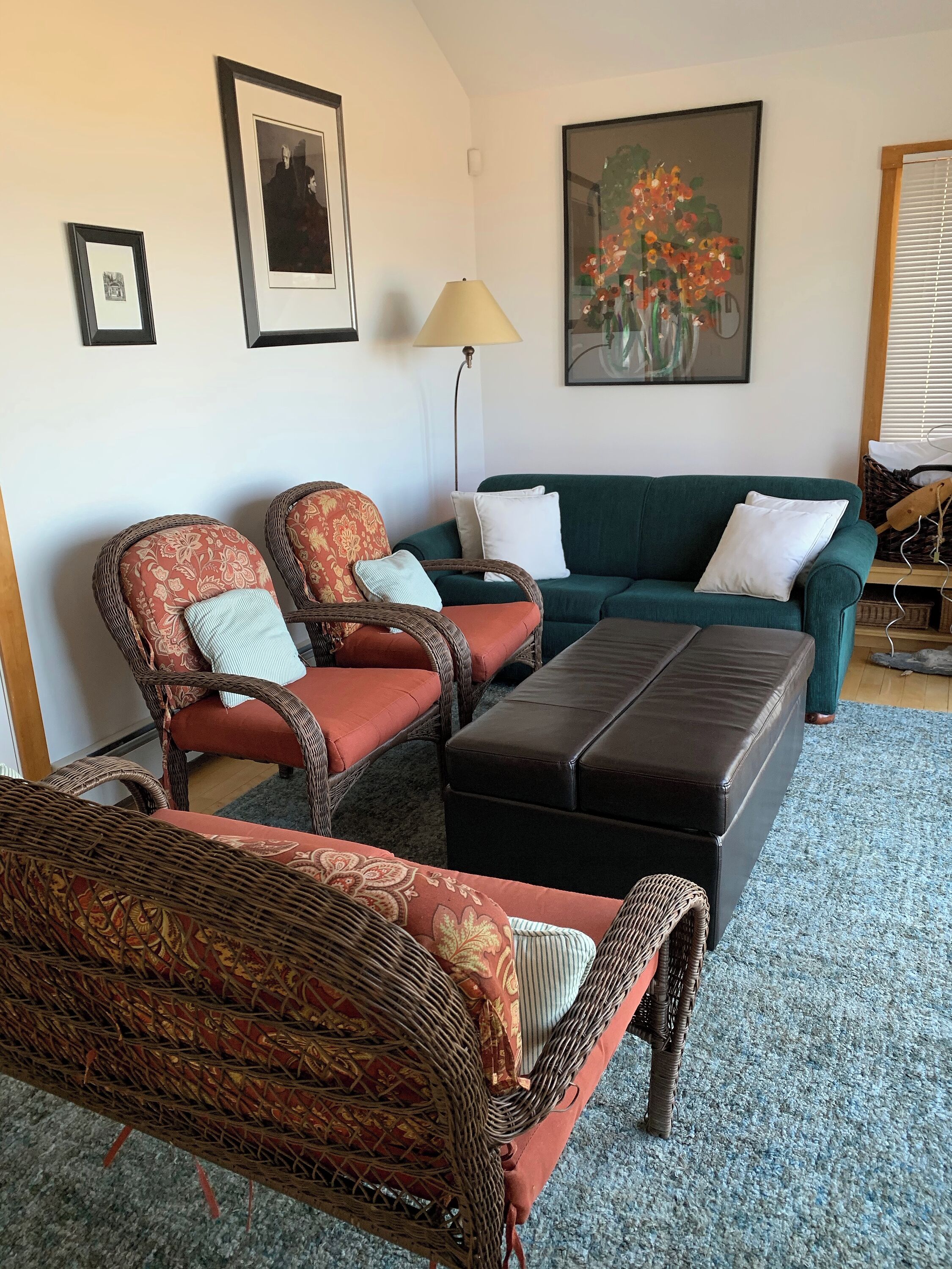 A living room with wicker furniture, a green sofa, and a lamp.