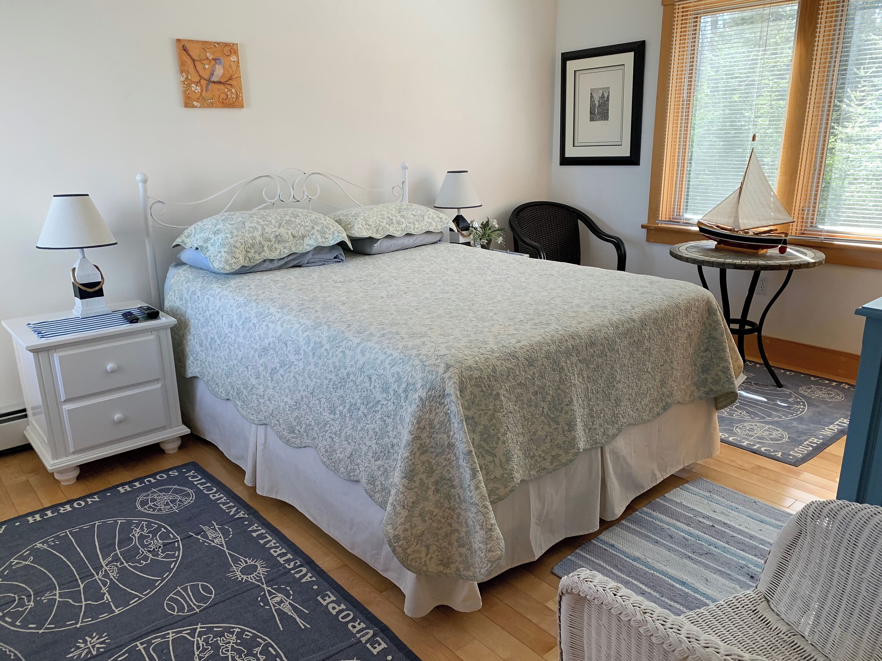 A neatly arranged bedroom with a bed, bedside tables, a chair, and a small table with a decorative item.