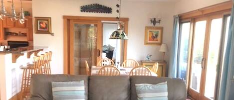 Uma sala de estar com um sofá de couro, uma mesa de centro de vidro e uma área de jantar com cadeiras e mesa de madeira.