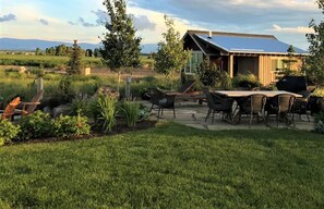 Una casa moderna con techo de paneles solares, un patio con mobiliario exterior y un jardín bien cuidado.