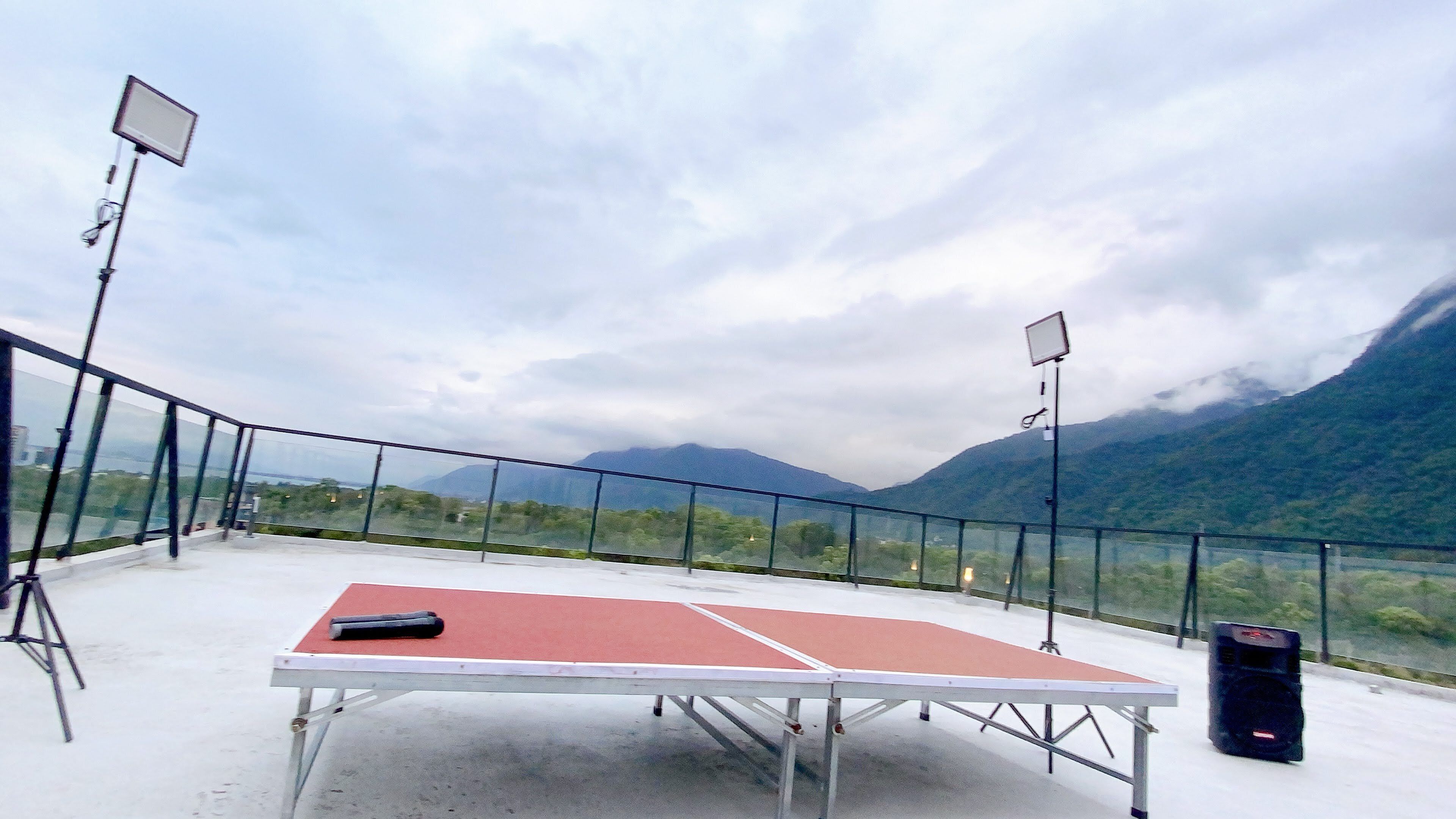 Mesa de pingue-pongue num terraço com vista panorâmica para montanhas.