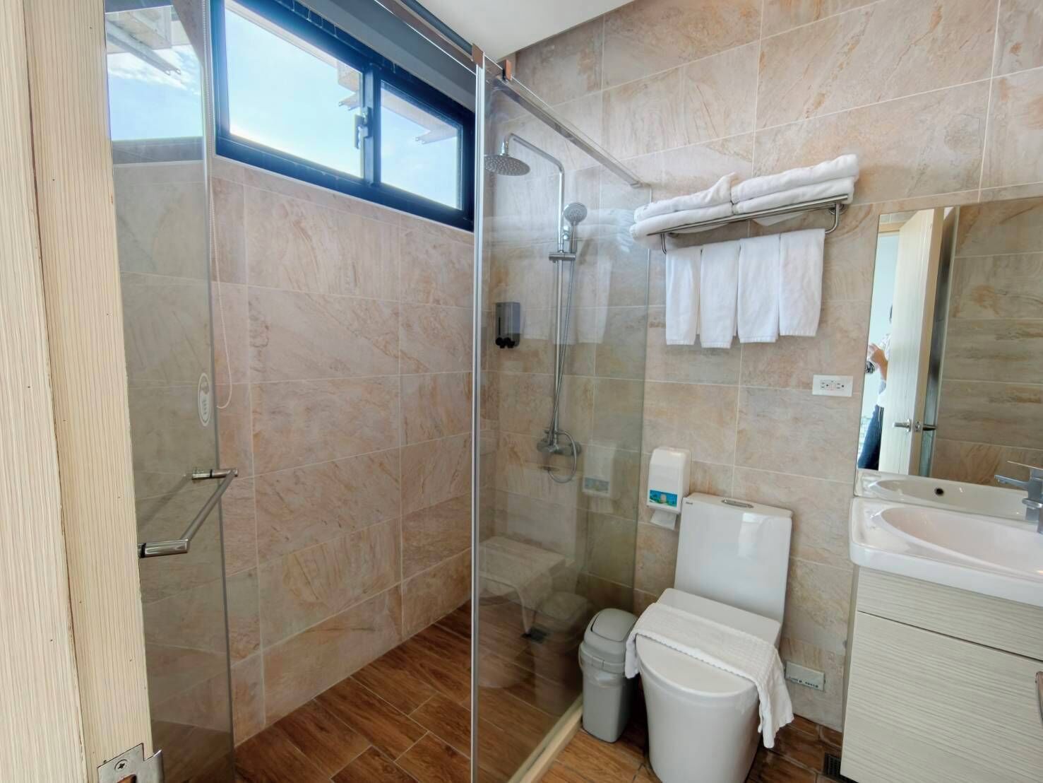 A modern bathroom with a glass-enclosed shower, a toilet, and a sink.