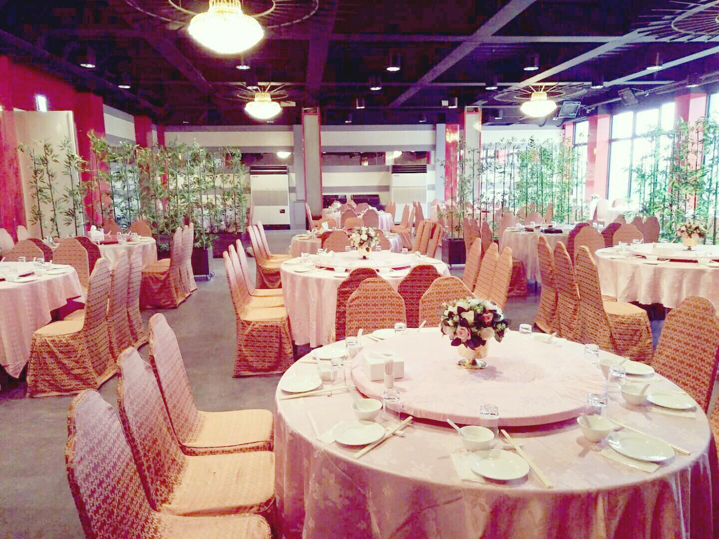 A banquet hall with round tables, chairs, and floral centerpieces.