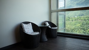 A room with wicker chairs and a small table, a large window with a view of greenery. - Starry Inn (Xincheng)