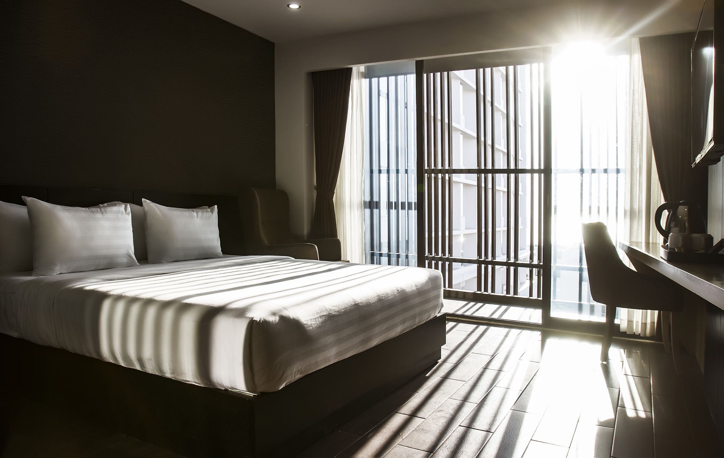 A hotel room with a large bed, a desk, and a view of the outside.