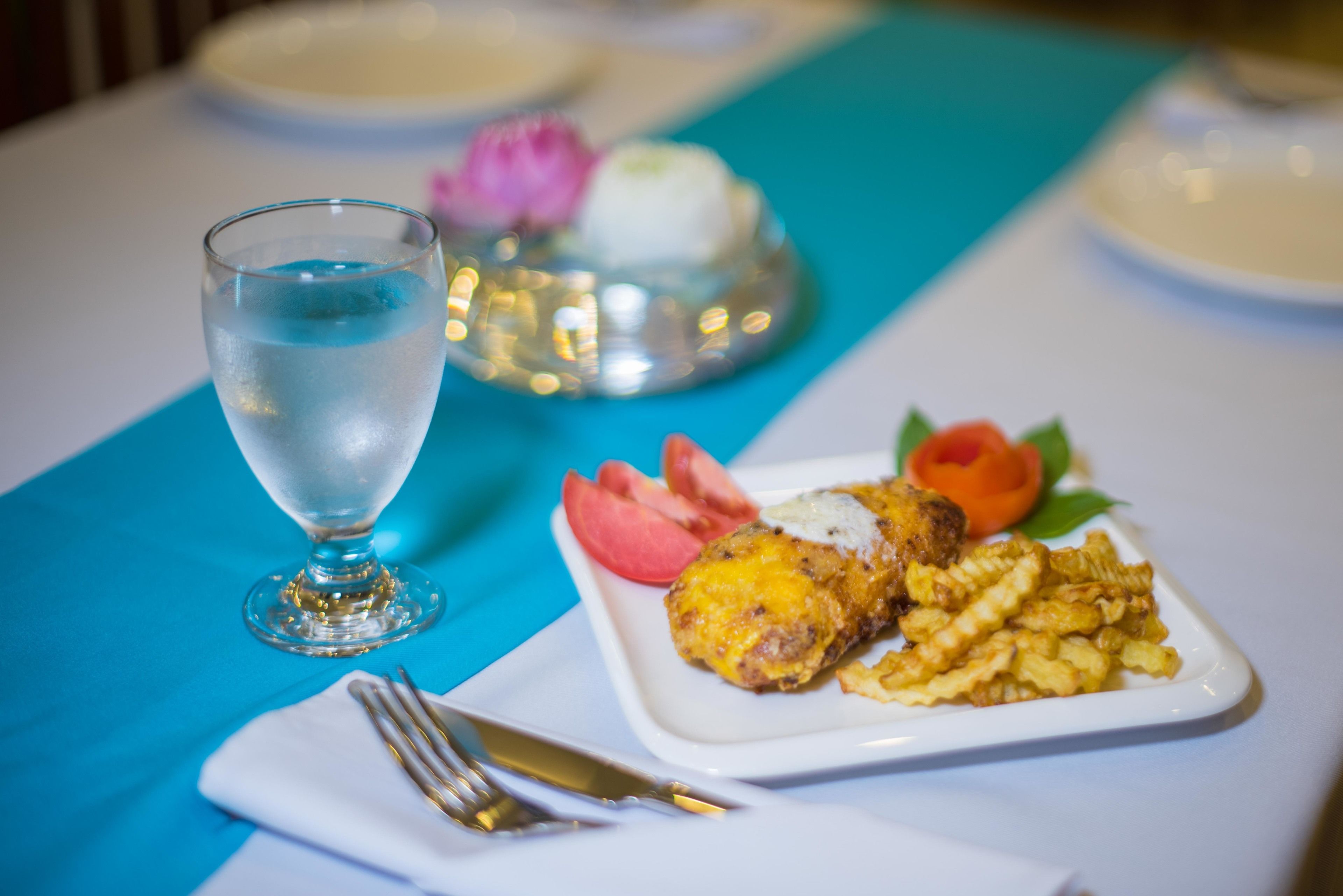 Una mesa puesta con un plato de comida, un vaso de agua y una servilleta con cubiertos.